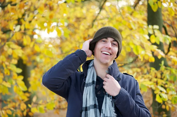 Portrait of a happy young man laughing outdoors with hat — Stock Photo, Image