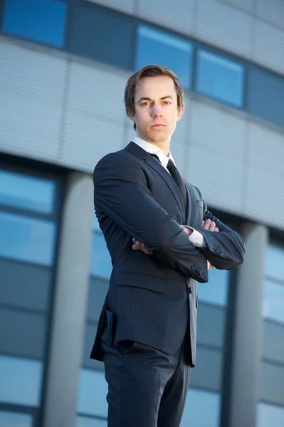 Confident young businessman standing outdoors with arms crossed — Stock Photo, Image
