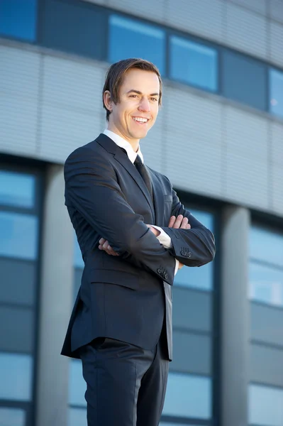 Joven hombre de negocios parado al aire libre sonriendo —  Fotos de Stock