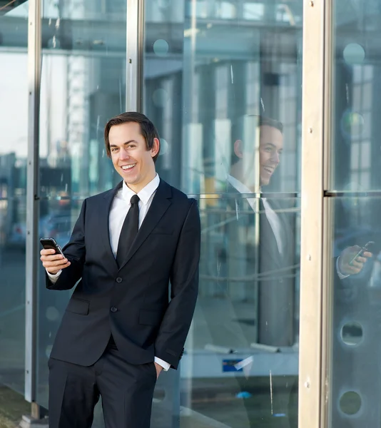 Homem de negócios feliz sorrindo ao ar livre com celular — Fotografia de Stock