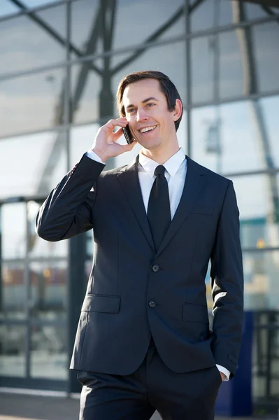 Businessman smiling and calling by mobile phone outdoors — Stock Photo, Image