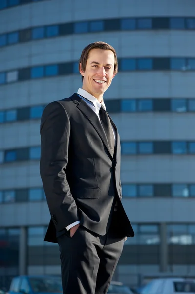Porträt eines hübschen jungen Geschäftsmannes, der vor dem Büro lächelt — Stockfoto