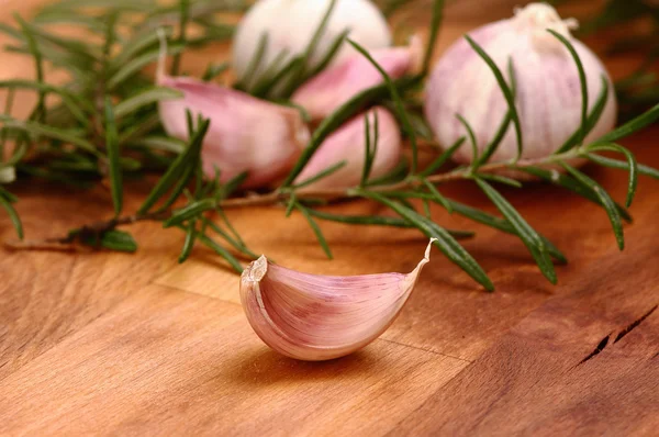 Frischer Knoblauch mit Rosmarin im Hintergrund — Stockfoto