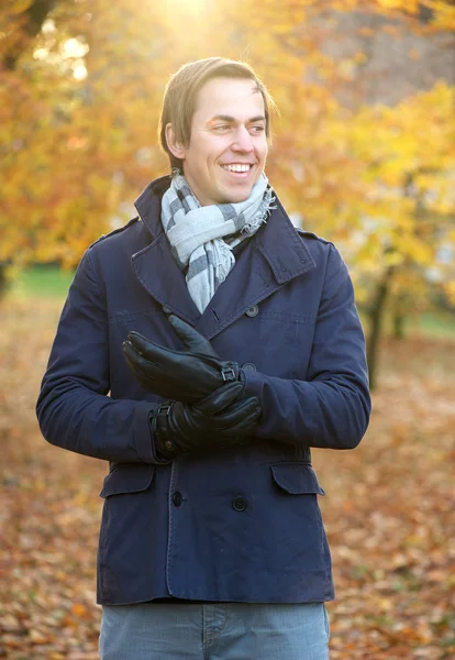 アウトドア ジャケットのスカーフと手袋に立っている男の笑みを浮かべてください。 — ストック写真