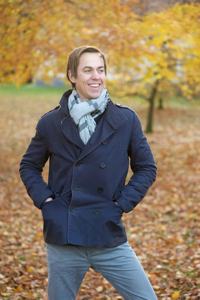 Sezon szczęśliwy młody człowiek uśmiechający się na zewnątrz w upadek — Zdjęcie stockowe