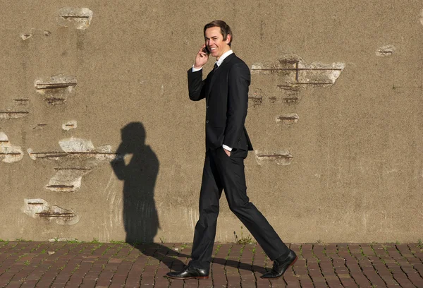 Homem de negócios feliz andando e falando no telefone móvel — Fotografia de Stock