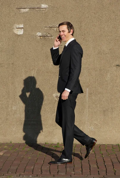 Homem de negócios sorrindo andando e conversando no celular — Fotografia de Stock