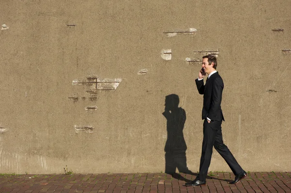 Affärsman promenader och pratar i mobiltelefon — Stockfoto