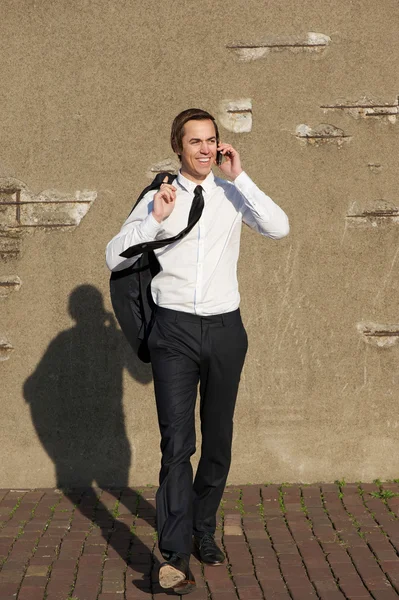 Rento liikemies kävelee ja puhuu puhelimessa ulkona — kuvapankkivalokuva