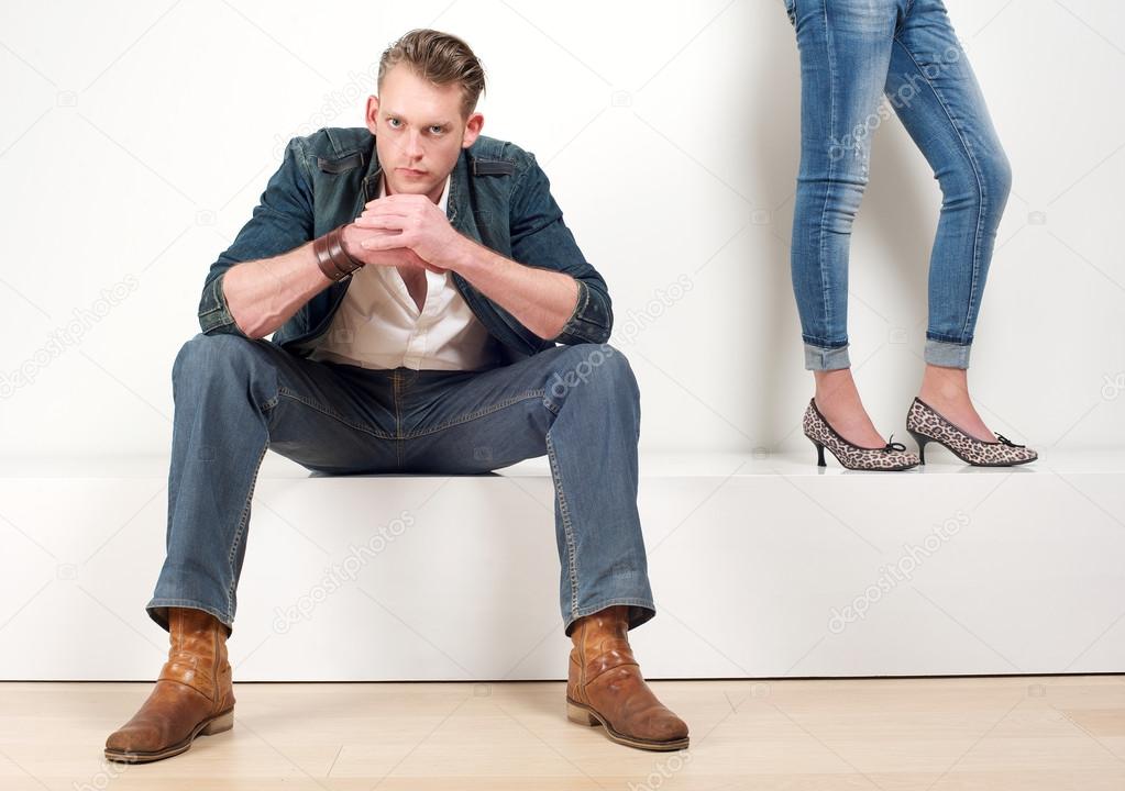 Attractive male model sitting with a pair of female legs on the side