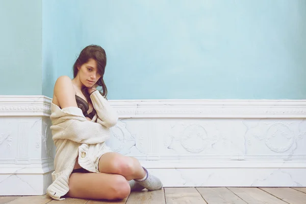 Giovane donna seduta da sola sul pavimento con maglione — Foto Stock