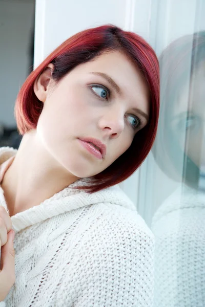 Woman looking out window with sad expression — Stock Photo, Image