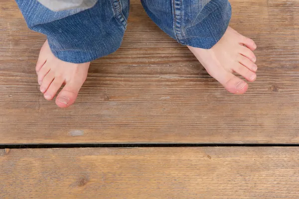 Ovansida av jeans och fötter från en liten flicka — Stockfoto