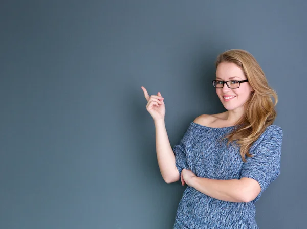 Genç kadın gülümseyerek ve parmak işaret — Stok fotoğraf