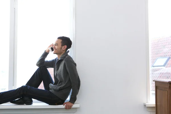 Young man laughing on mobile phone at home — Stock Photo, Image