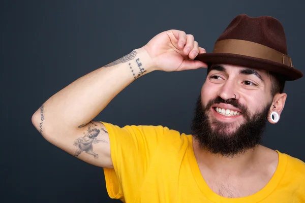 Homem sorrindo com chapéu no fundo cinza — Fotografia de Stock