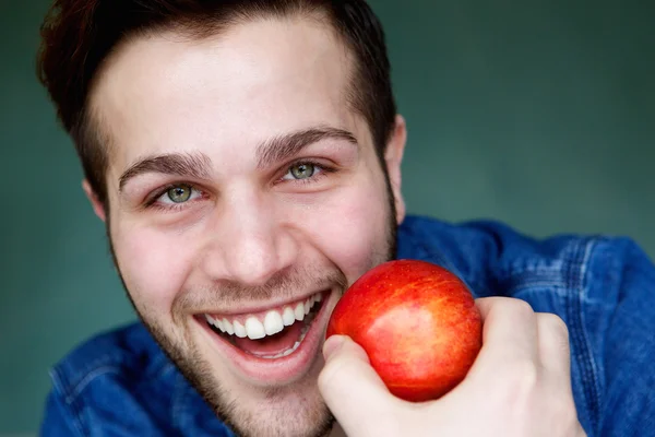 Homme souriant tenant une pomme rouge — Photo