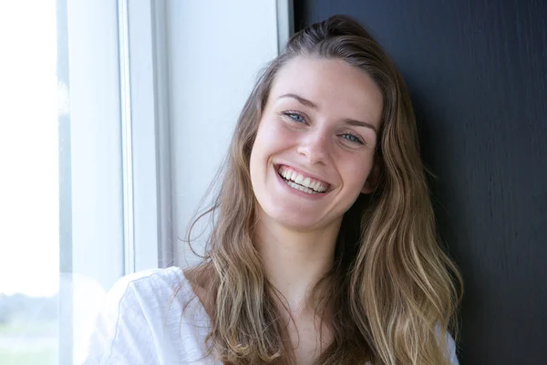 Mujer sonriendo por la ventana en casa — Foto de Stock