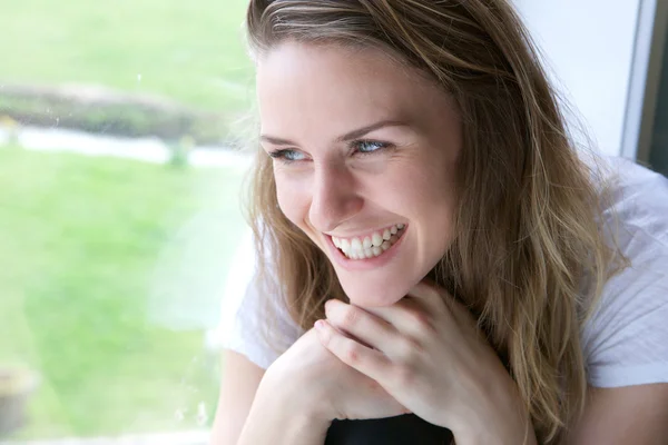 Jovem mulher sorrindo pela janela — Fotografia de Stock