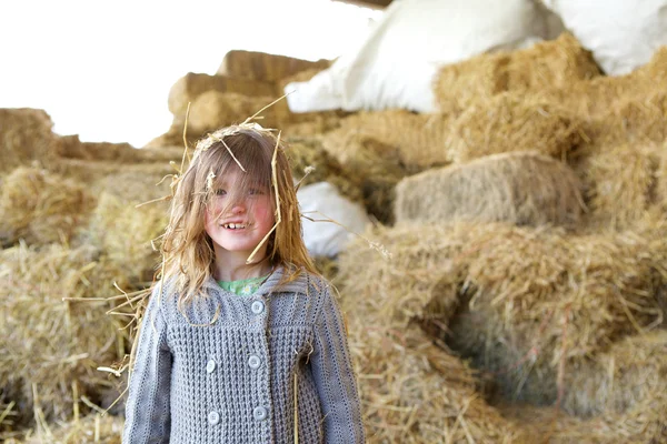 Girl smiling on a farm with hay in hair — Stock Photo, Image