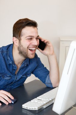 adam gülüyor ve bilgisayar ekranına bakarak