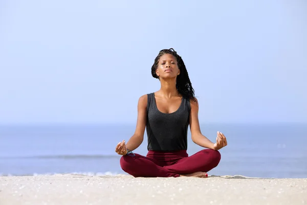 Mujer sentada en yoga posando en la playa — Foto de Stock