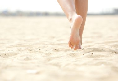 Woman barefoot walking on beach clipart