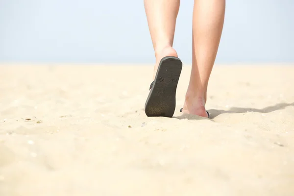 Сандалии, идущие по песку на пляже — стоковое фото