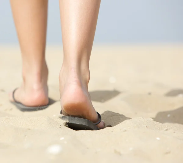 Woman walking in slippers on sand — Stock Photo, Image