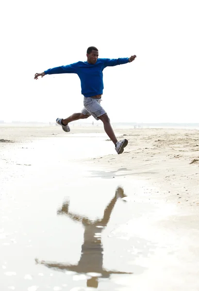 Jeune homme athlétique qui court à la plage — Photo