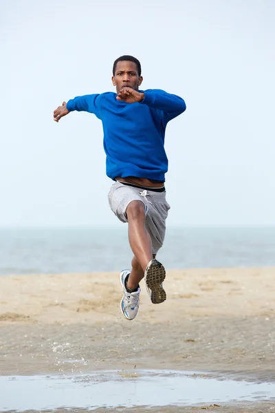 Jovem atleta masculino correndo na praia . — Fotografia de Stock
