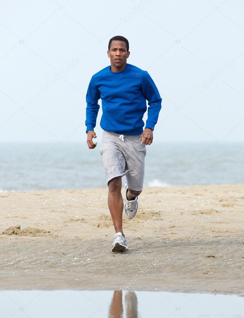 African american man jogging at beach