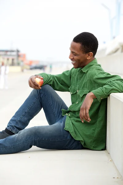 Hombre negro sonriendo y sosteniendo manzana —  Fotos de Stock