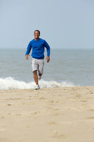 Hombre sonriendo y corriendo en la playa — Foto de Stock