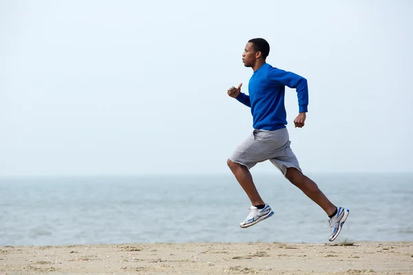 Jonge atletische man loopt op het strand — Stockfoto