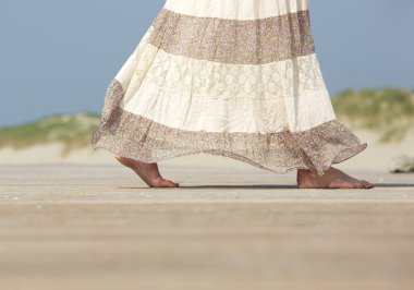 yalınayak kumsalda yürüyen kadın