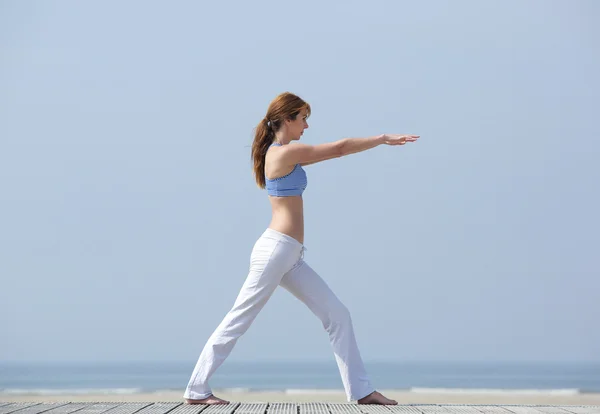 Kobieta robi stretch jogi na plaży — Zdjęcie stockowe