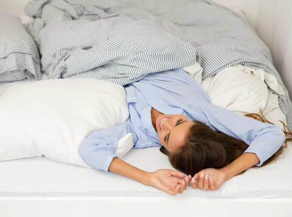 Jovem mulher acordada na cama sorrindo — Fotografia de Stock