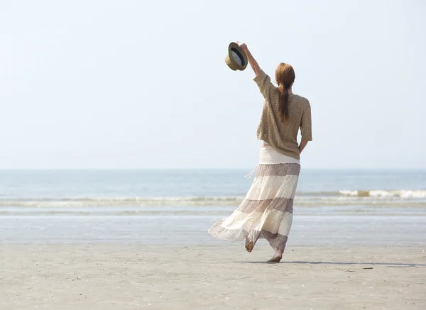 Donna che cammina sulla spiaggia con il braccio alzato — Foto Stock