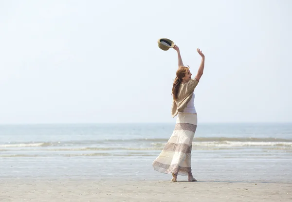 Mujer caminando en la playa con los brazos levantados — Foto de Stock