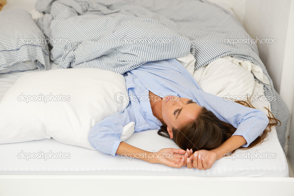 Young woman awake in bed looking up 