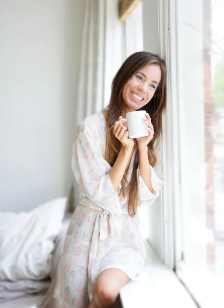 Mujer sentada junto a la ventana bebiendo té —  Fotos de Stock