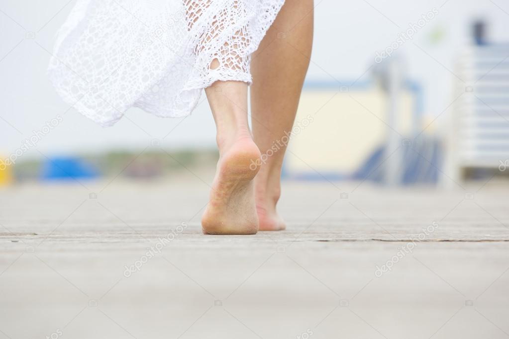 Low angle barefoot woman walking away