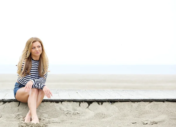 Jonge vrouw zitten op het strand denken — Stockfoto