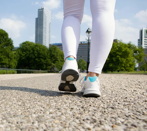 Ung kvinna fötter gå i stadsparken — Stockfoto