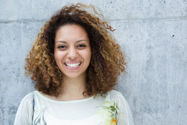 Beautiful young woman with curly hair smiling outdoors