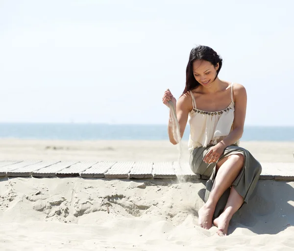 Mulher sentada na praia com areia na mão — Fotografia de Stock