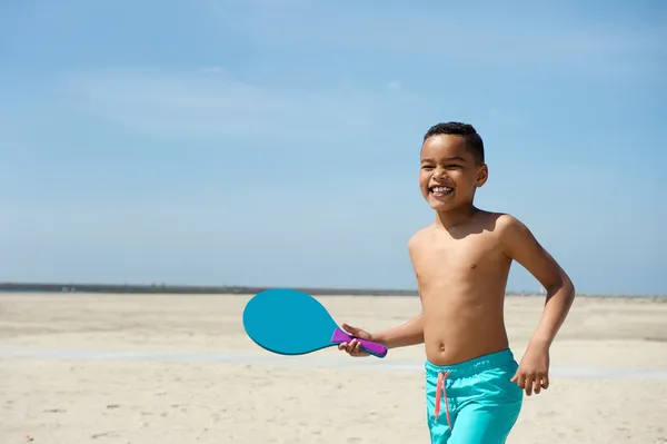 Junge spielt Paddelball am Strand — Stockfoto