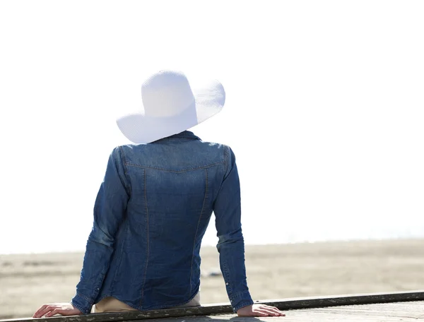 Vrouw zitten door strand met zomer hoed — Stockfoto