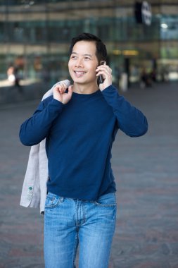 Asyalı adam cep telefonu ile yürüyor